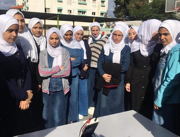 Female high school students inspect solar panel at high school yard