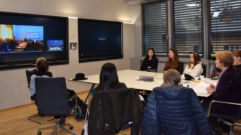 Project team in Austria in front of big screens in a room, connected to Palestinian team virtually
