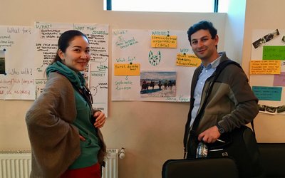 Two scholars in front of flip chart presenting their work