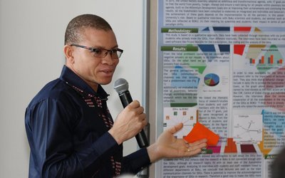 Vincent-Paul Sanon talking into a microphone with a poster next to h im