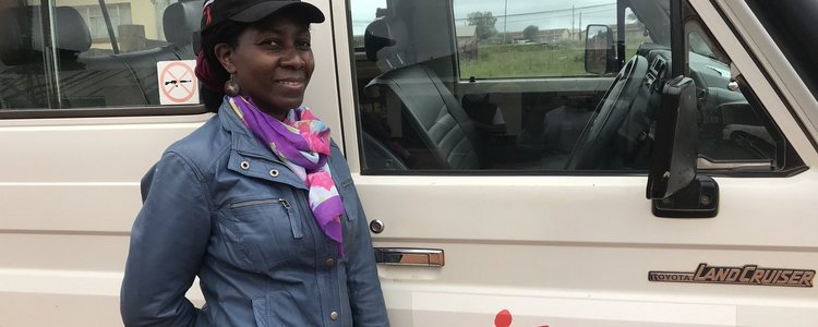 Alumna from Uganda in front of car of "Doctors without borders"
