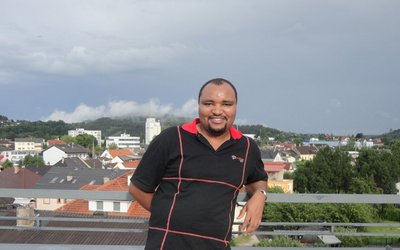 photo of former scholarship holder on a balcony with city view