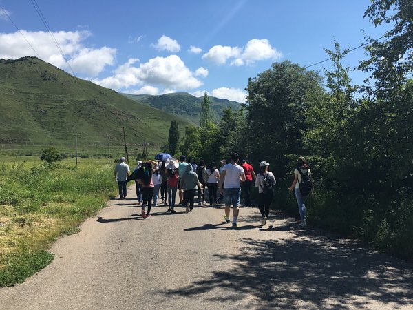 Group of people walking along a street in green hilly surroundings