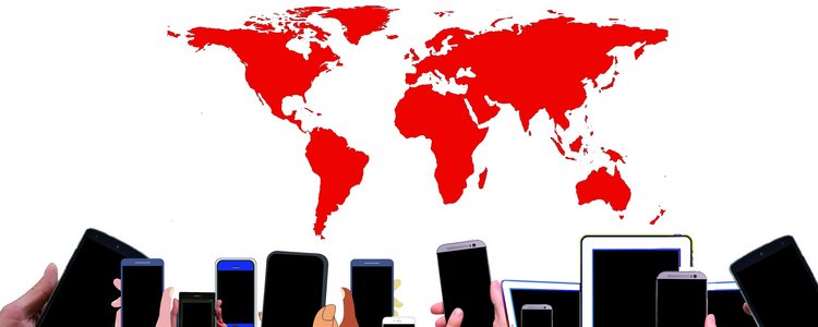 Fourteen smartphones and tablets are being held up by hands in front of a red-coloured world map in the back.