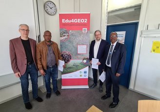 Four men standing in front of the project roll-up
