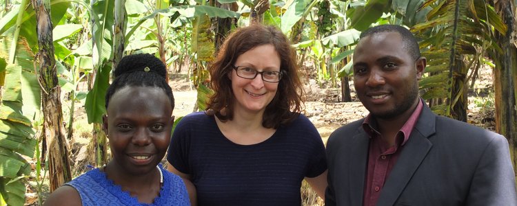 Two APPEAR scholars and one APPEAR representative posing for a photo in front of banana plants