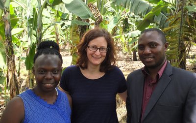 Two APPEAR scholars and one APPEAR representative posing for a photo in front of banana plants
