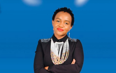 Sonnia Musyoka sitting on a chair in front of a blue background