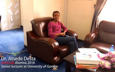 A woman sitting in an armchair, holding a notebook and a pen in her hands