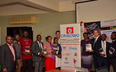 Group of people posing for a group picture next to a CRISOWO poster